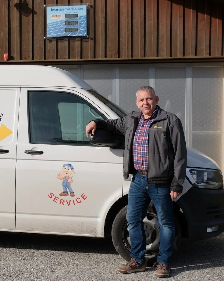 Mann in Jacke und Jeans lehnt an einem Servicefahrzeug von Elektro Eisl