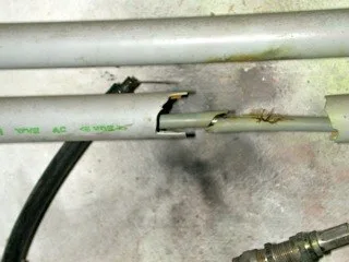 Beschädigte Elektroleitung neben einem aufgeplatzten Schutzrohr