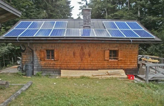 Holzhütte mit Photovoltaikmodulen auf dem Dach